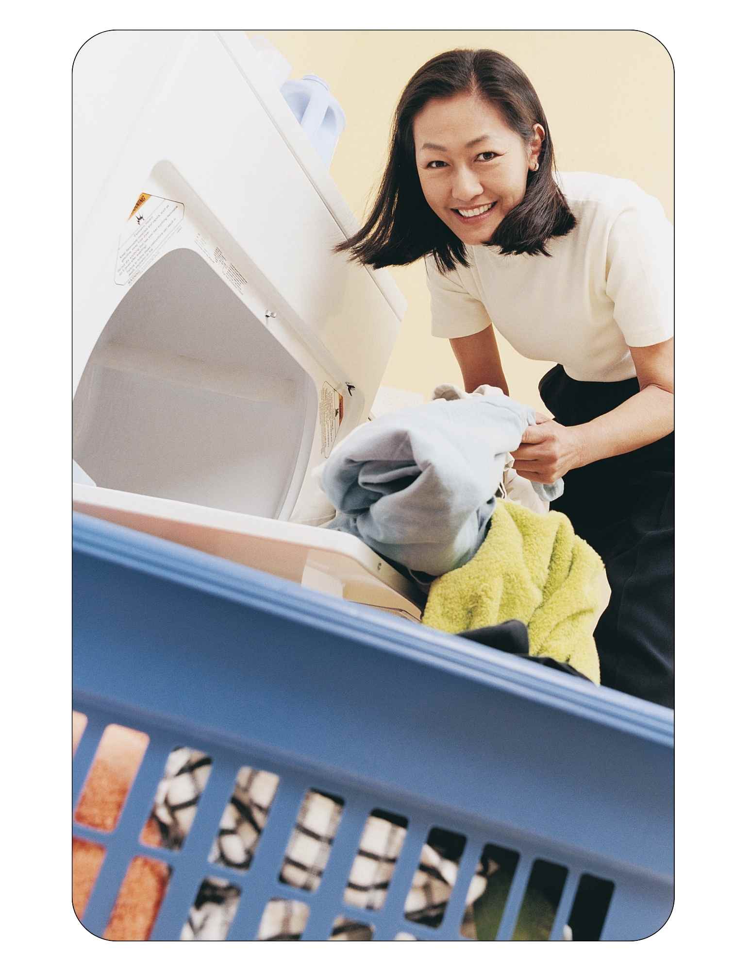 Femme sortant des vêtements d'une sécheuse dont les tuyaux ont été nettoyés.